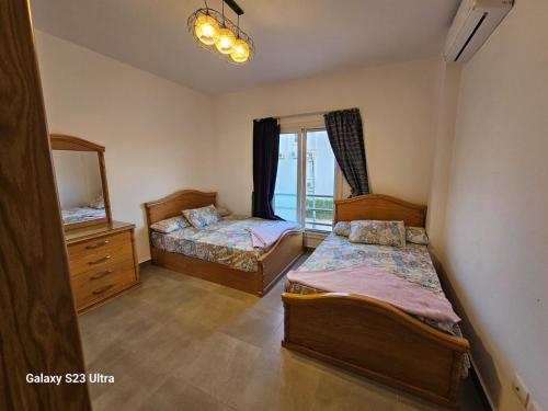 ein Schlafzimmer mit zwei Betten und einem Spiegel in der Unterkunft Amwaj sidi abed el rahman in Banī Ghālib