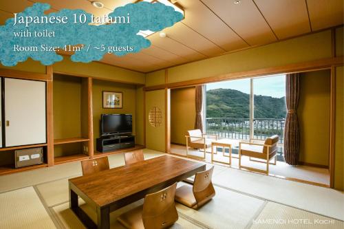 a living room with a wooden table and a large window at KAMENOI HOTEL Kochi in Ino