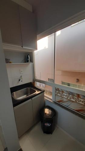 a small kitchen with a sink and a trash can at Residencial Fênix II in Florianópolis
