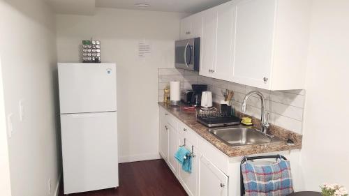 una cucina con un frigorifero bianco e un lavello di Two luxury bedrooms in the basement a Winnipeg