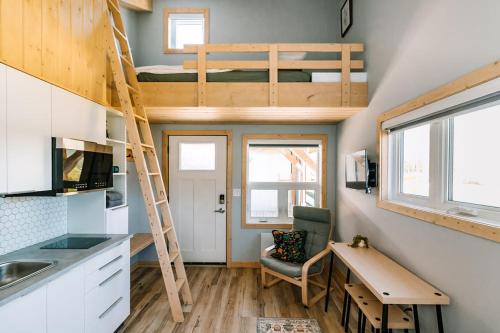 a tiny house with a loft bed and a desk at Roamer's Nook in Nordegg