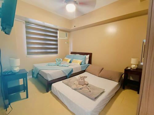 a bedroom with two beds and a couch and a window at 1205T2 Avida Riala IT Park 1BR Unit 400Mbps Internet in Cebu City