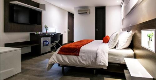 Un dormitorio con una cama, un escritorio y un televisor. en Hotel Loyds, en Medellín
