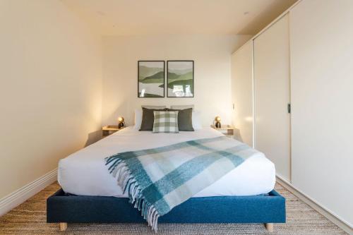a bedroom with a large bed with a blue foot stool at Rivulet Retreat - Cosy South Hobart Home & Parking in West Hobart