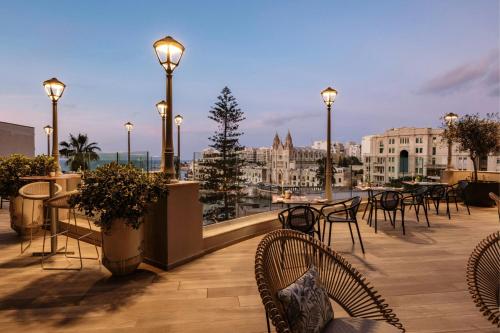 a rooftop patio with tables and chairs and lights at Malta Marriott Resort & Spa in St Julian's