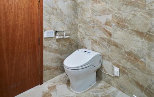 a white toilet in a bathroom with marble walls at GoldOne Hotel & Suites in Seogwipo
