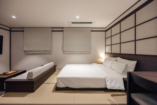 a bedroom with a white bed and a couch at Aank Ryokan Hotel Suwon in Suwon