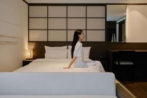 a woman sitting on top of a bed at Aank Ryokan Hotel Suwon in Suwon