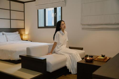 a woman sitting on a couch in a hotel room at Aank Ryokan Hotel Suwon in Suwon