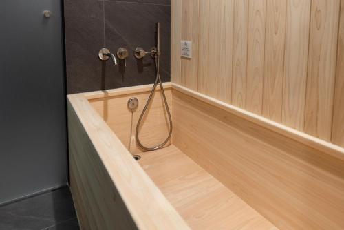 a bathroom with a shower with a hose on the wall at Aank Ryokan Hotel Suwon in Suwon