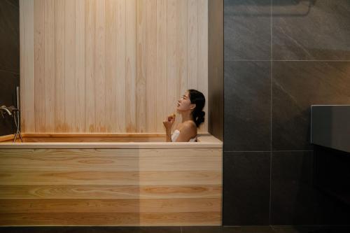 a woman taking a bath in a bath tub at Aank Ryokan Hotel Suwon in Suwon