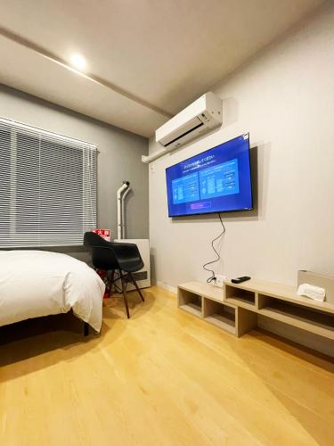 a bedroom with a bed and a flat screen tv on the wall at カレラ豊平2nd in Sapporo