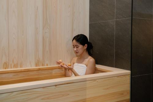 a woman sitting in a bath tub eating food at Aank Ryokan Hotel Suwon in Suwon