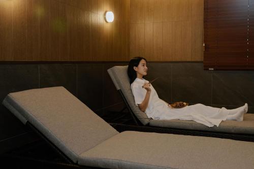 a woman sitting in a chair in a room at Aank Ryokan Hotel Suwon in Suwon