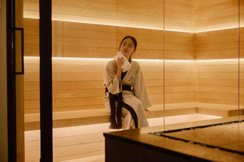 a woman is sitting in a sauna at Aank Ryokan Hotel Suwon in Suwon