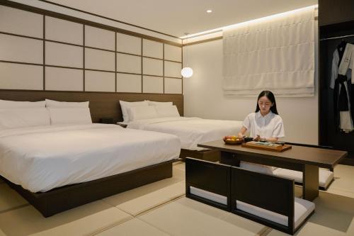a woman in a hotel room with two beds at Aank Ryokan Hotel Suwon in Suwon