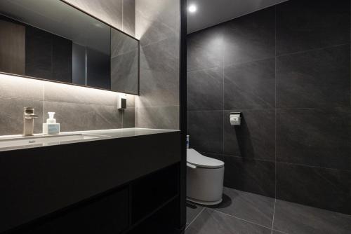 a bathroom with a toilet and a sink and a mirror at Aank Ryokan Hotel Suwon in Suwon