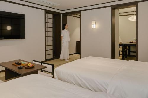 a man standing in a room with two beds at Aank Ryokan Hotel Suwon in Suwon