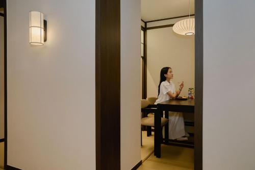 a woman sitting at a table in a room at Aank Ryokan Hotel Suwon in Suwon