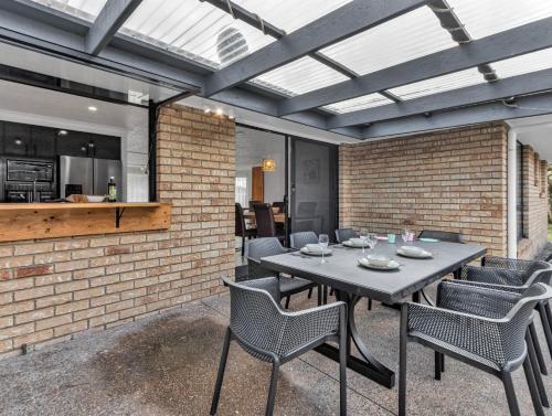 a patio with a table and chairs and a brick wall at Ultimate Beachside Haven in Cabarita - Pet Friendly in Cabarita Beach