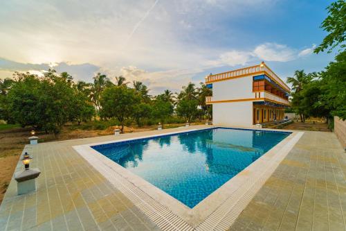 a swimming pool in front of a building at Neithal Farm Resort with Swimming Pool by Roscotel in Puducherry