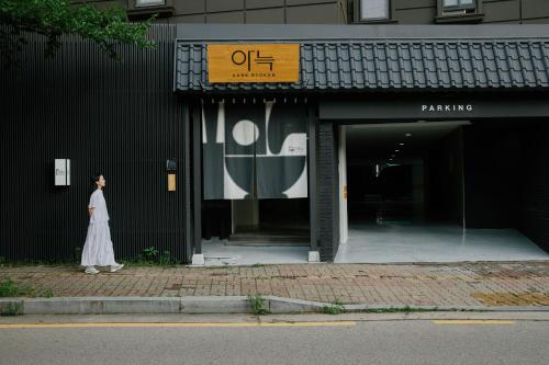 a woman in a white dress standing outside of a building at Aank Ryokan Hotel Suwon in Suwon