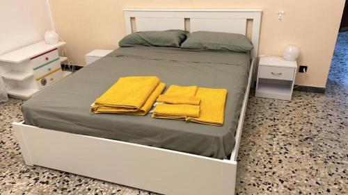 a white bed with two yellow towels on it at PM 1 Via Ovidio Guest House in Leporano Marina