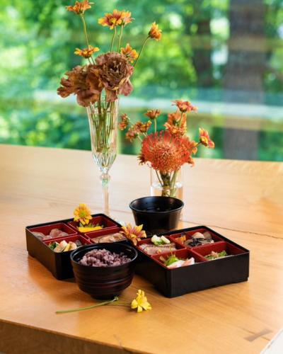 two trays of food sitting on a table with flowers at Hakuba Aurora Chalet by Jade Group in Hakuba