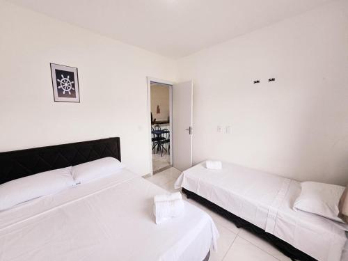 two beds in a room with white walls at Residencia Praia Dos Corais H100 in Santa Cruz Cabrália
