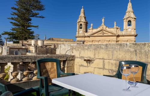 a table with two chairs and a table with wine glasses at Casa Naxxar 4 Floor Townhouse and Private Pool in Naxxar