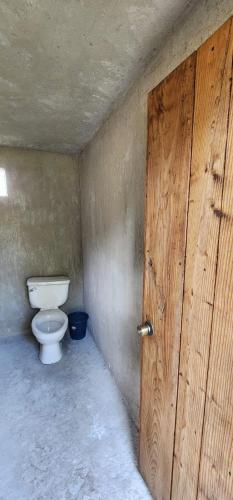a bathroom with a toilet and a wooden door at Cabaña El Descanso del Carpintero in La Marquesa