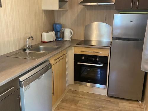 une petite cuisine avec un évier et un réfrigérateur dans l'établissement Chalet 2 chambres au calme, piscine chauffée, près du lac du Jaunay et plages de Vendée - FR-1-783-10, à La Chapelle-Hermier