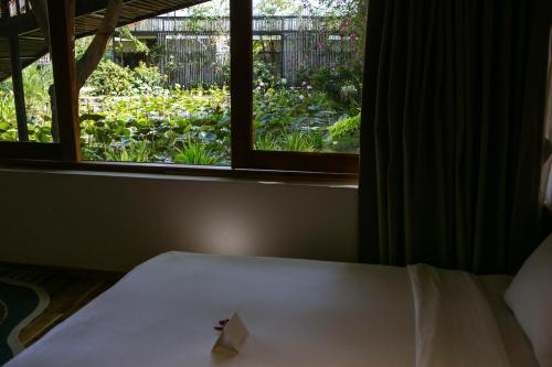 a room with a bed and a window with flowers at Tổ Boutique Garden in La Gi