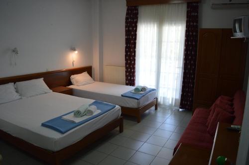 a hotel room with two beds and a couch at Galanis Studios and Apartments in Platamonas