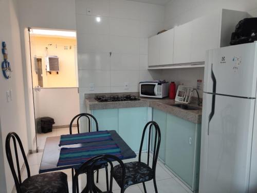 a kitchen with a table and chairs and a refrigerator at Residencial Prais Dos Corais H106 in Santa Cruz Cabrália