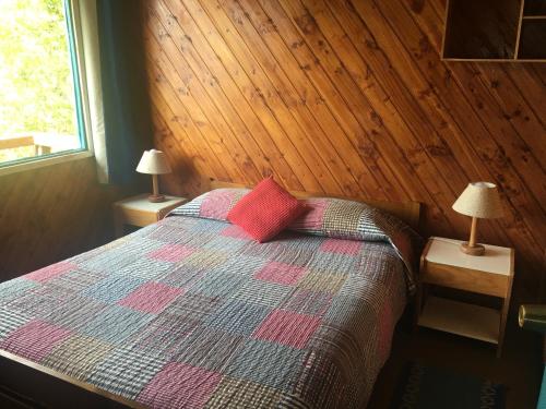 a bedroom with a bed with two lamps on tables at Cabaña Celeste - Acceso directo a playa lago Caburgua y cancha de tenis - direct access Beach in Caburgua Lake and tenis court in Pucón