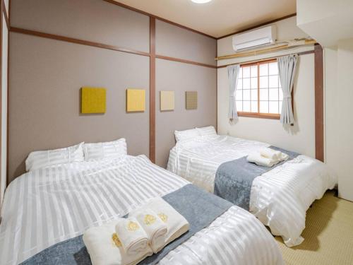 a bedroom with two beds and a window at Residential Hotel GRAN梅香 Newly opened Hotel Baika Family friendly Free parking 10 minutes to USJ in Osaka