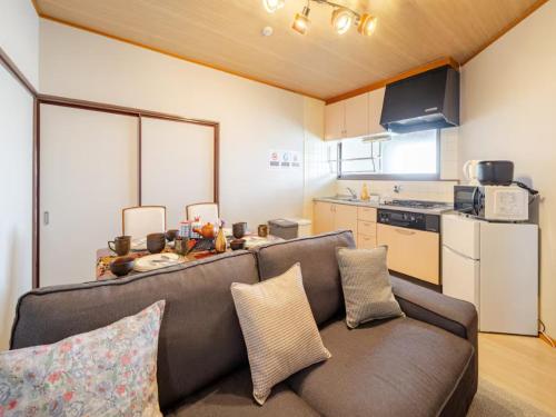 a living room with a couch and a kitchen at Residential Hotel GRAN梅香 Newly opened Hotel Baika Family friendly Free parking 10 minutes to USJ in Osaka