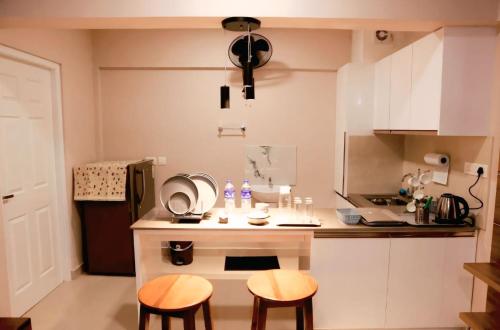 a small kitchen with a white counter and two stools at Lavender Airport Suite in Nedumbassery