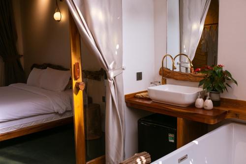 a bathroom with a sink and a bed in a room at Tổ Boutique Garden in La Gi