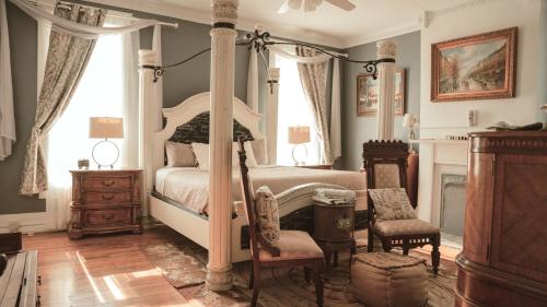 a bedroom with a four poster bed and a chair at The Magnolia Mansion 6 Minutes to Broadway on 4 Acres in Nashville