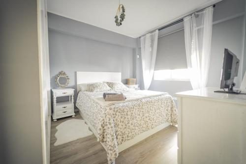 a white bedroom with a bed and a television at Apartamento cerca zona comercial in Narón