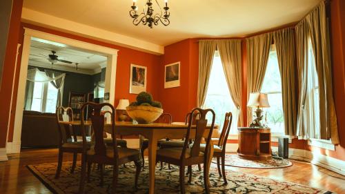a dining room with orange walls and a table and chairs at The Magnolia Mansion 6 Minutes to Broadway on 4 Acres in Nashville