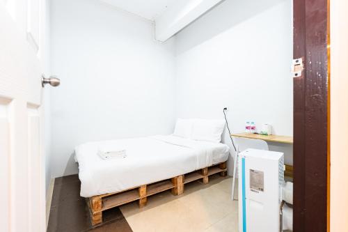 a small room with a bed and a refrigerator at The Hidden Khaosan - เดอะ ฮิดเด้นข้าวสาร in Bang Bua Thong Railway Station