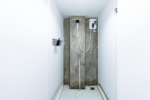 a shower in a white bathroom with a shower at The Hidden Khaosan - เดอะ ฮิดเด้นข้าวสาร in Bang Bua Thong Railway Station