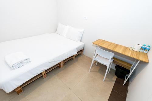 a small bedroom with a bed and a desk at The Hidden Khaosan - เดอะ ฮิดเด้นข้าวสาร in Bang Bua Thong Railway Station