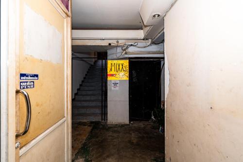 an empty hallway with stairs and a yellow sign at The Hidden Khaosan - เดอะ ฮิดเด้นข้าวสาร in Bang Bua Thong Railway Station