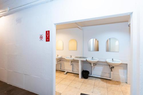 a bathroom with three sinks and two mirrors at The Hidden Khaosan - เดอะ ฮิดเด้นข้าวสาร in Bang Bua Thong Railway Station