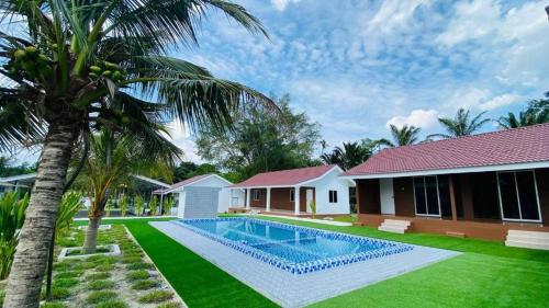 a villa with a swimming pool in front of a house at Farmstay Laman Zulfaqar in Lahat