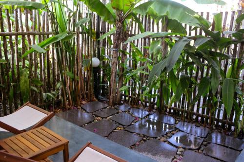 a bench and a chair in front of a bamboo fence at Tổ Boutique Garden in La Gi